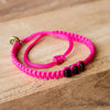 Black Chasqui Strawberry Pink bracelets that help children on wood