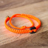Black Raymi Crayola Orange bracelets that fight poverty on wood
