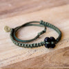 Black Tinkus Military Green donation bracelets on wood
