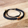 Brown Raymi Carbon Black bracelets that fight poverty on wood