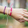 White Raymi Strawberry Pink bracelets that fight poverty on wrist