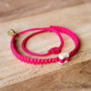 White Raymi Strawberry Pink bracelets that fight poverty on wood