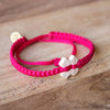 White Tinkus Strawberry Pink donation bracelets on wood